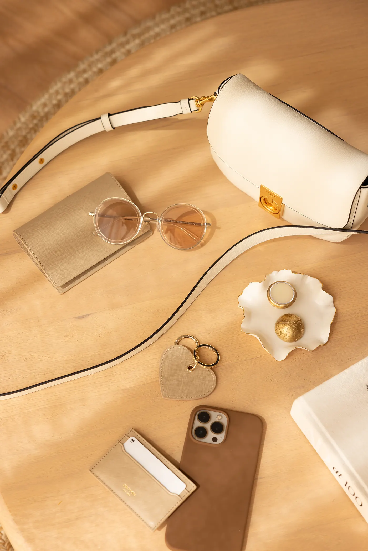 A brass globe on a table with a handbag, sunglasses and a phone