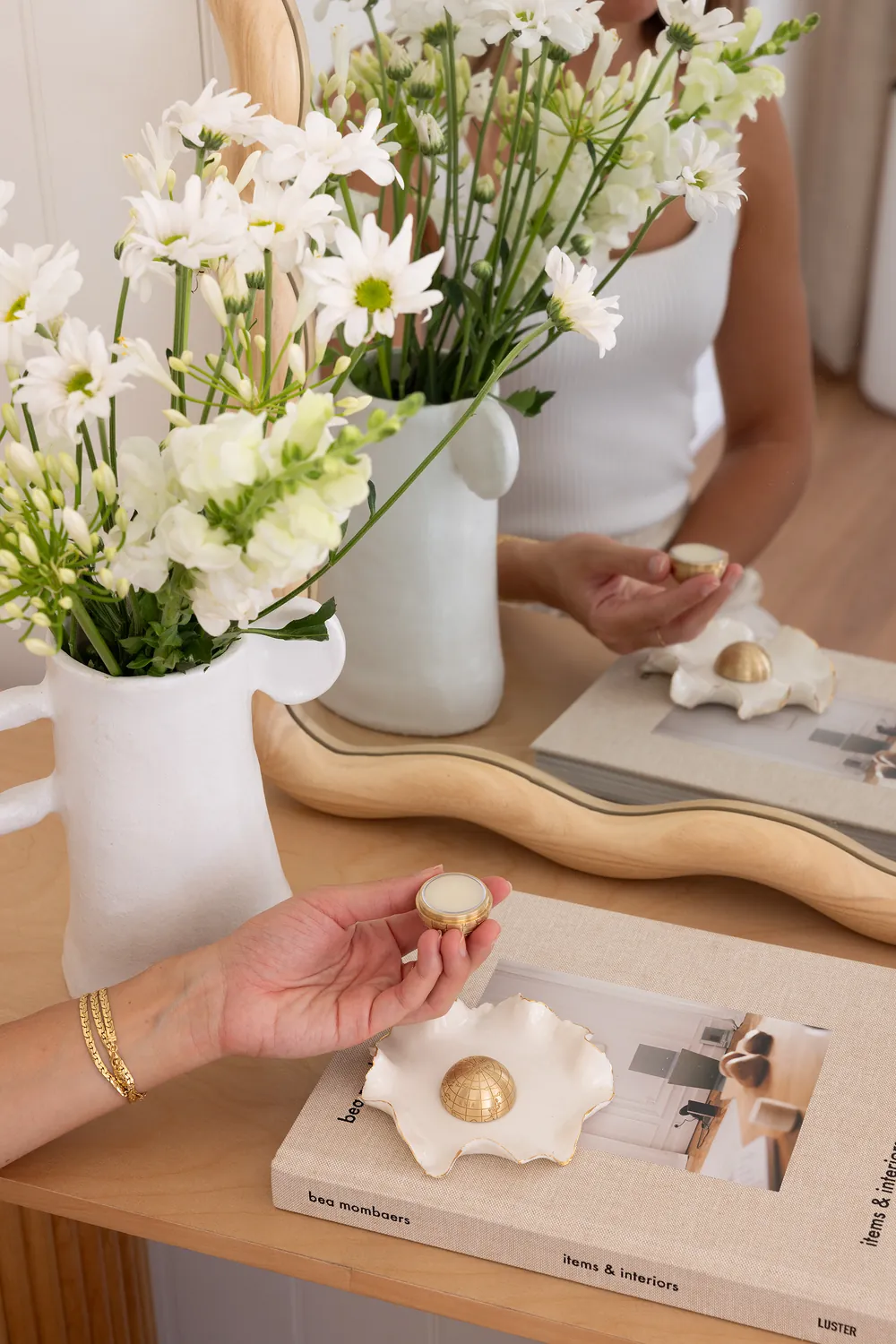 A brass globe on a ceramic dish beside white flowers